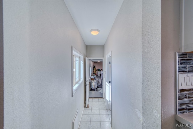 hallway with light tile patterned floors and a textured wall