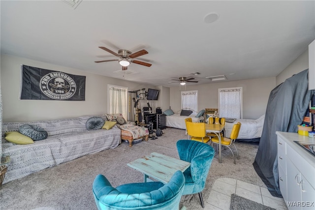 living area with attic access, light colored carpet, visible vents, and light tile patterned floors