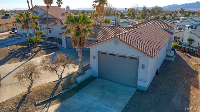 mediterranean / spanish house with a mountain view, concrete driveway, a tile roof, and a residential view