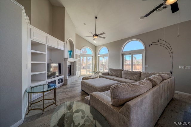 living area featuring a ceiling fan, a tile fireplace, high vaulted ceiling, and dark wood-style floors