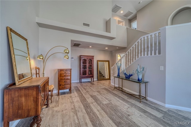 foyer entrance featuring baseboards, visible vents, and light wood-style floors