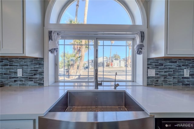 room details with tasteful backsplash, light countertops, and white cabinetry