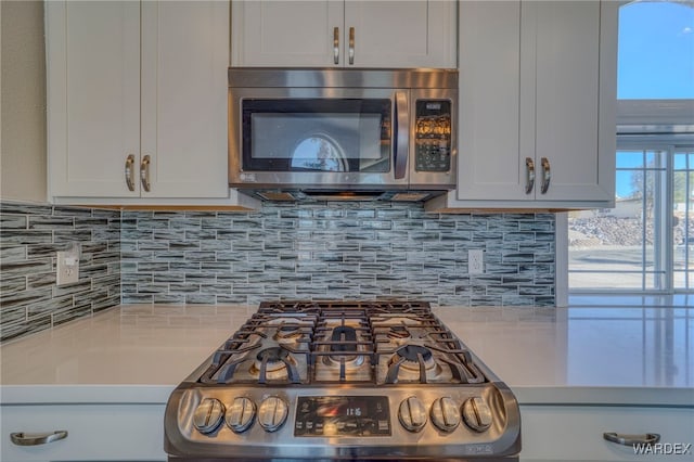 kitchen with white cabinets, backsplash, stainless steel appliances, and light countertops