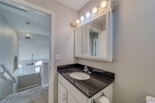 bathroom with a textured wall, visible vents, a ceiling fan, and vanity