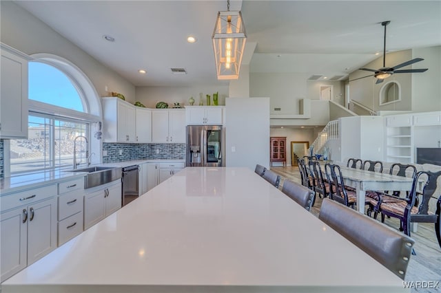 kitchen with a large island, light countertops, appliances with stainless steel finishes, open floor plan, and white cabinets