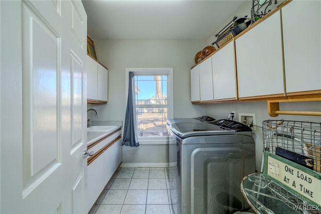 laundry room featuring light tile patterned floors, washing machine and clothes dryer, cabinet space, and baseboards