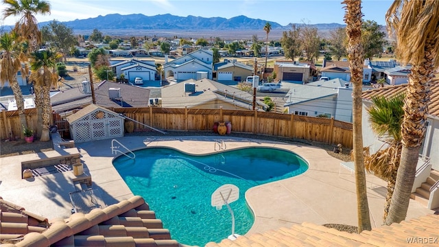 view of swimming pool featuring a fenced backyard, a mountain view, a residential view, a fenced in pool, and a patio area