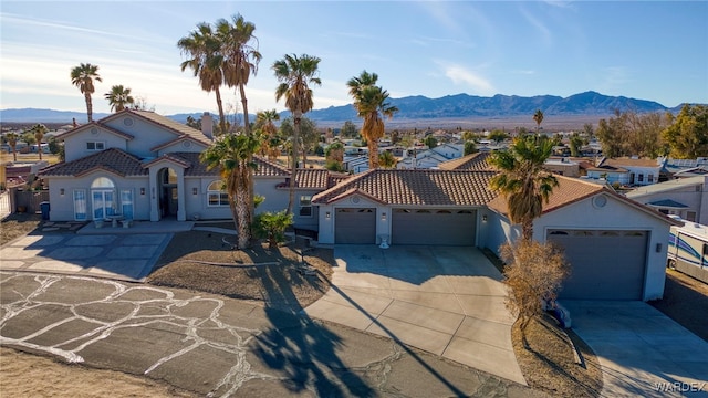 view of front of property featuring an attached garage, a residential view, a mountain view, and concrete driveway