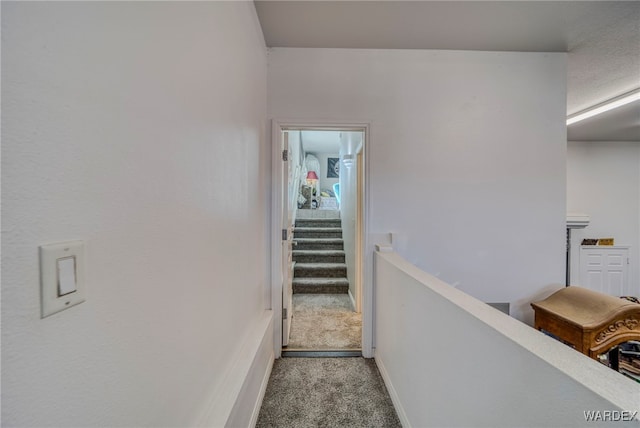 hallway with baseboards and light colored carpet