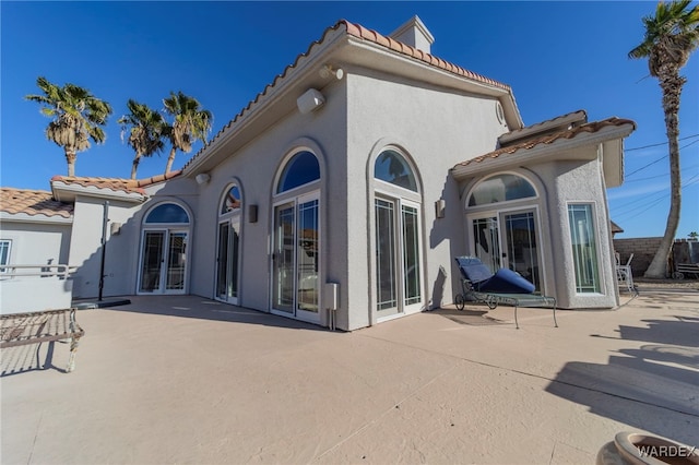 back of property featuring a patio, french doors, a tiled roof, and stucco siding