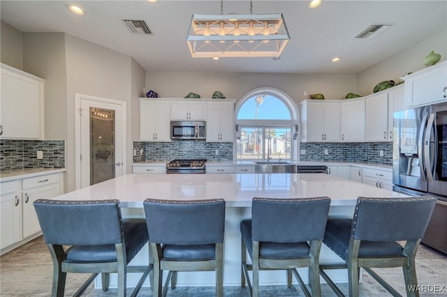 kitchen featuring stainless steel appliances, light countertops, a kitchen island, and visible vents