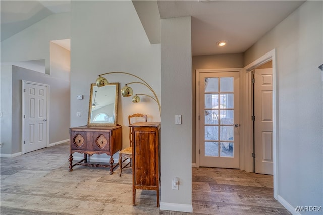 entryway featuring vaulted ceiling, light wood-style flooring, and baseboards