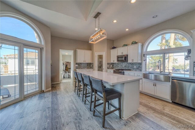 kitchen with appliances with stainless steel finishes, light countertops, white cabinetry, and a sink