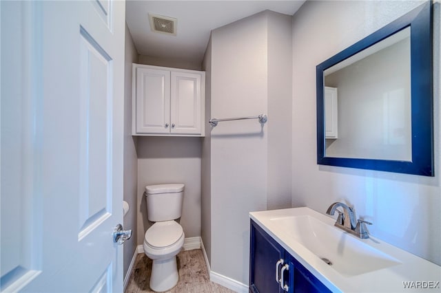 bathroom featuring toilet, vanity, visible vents, and baseboards