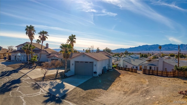 view of front of home featuring a mountain view, concrete driveway, fence, and a residential view