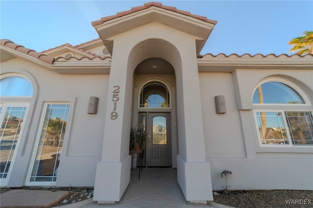 entrance to property with a tiled roof and stucco siding