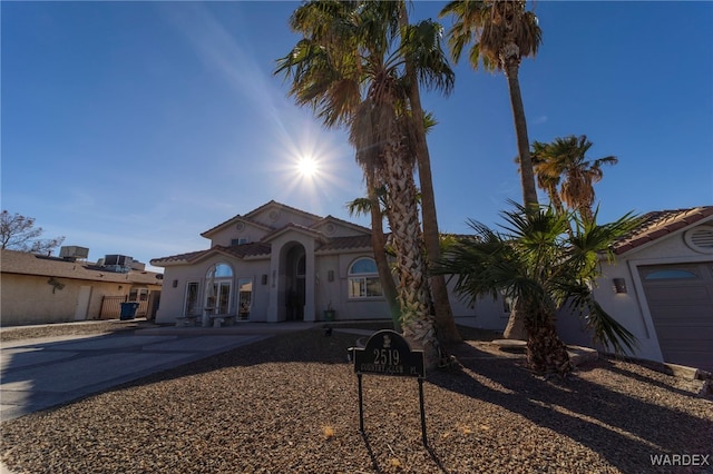 mediterranean / spanish home with a tile roof, driveway, and stucco siding