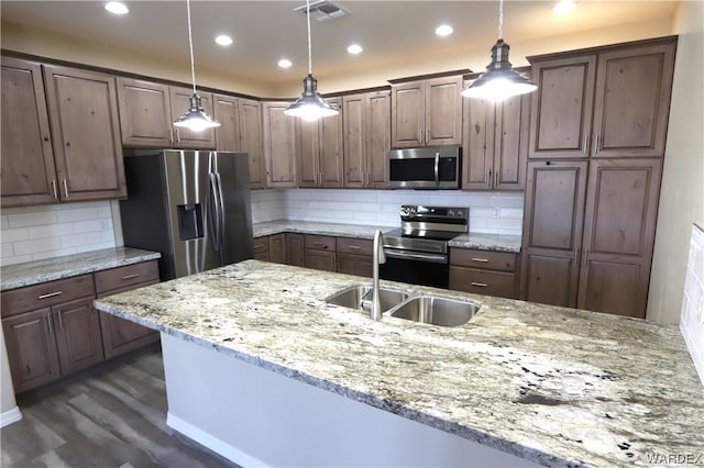 kitchen with visible vents, stainless steel appliances, light stone counters, and decorative light fixtures