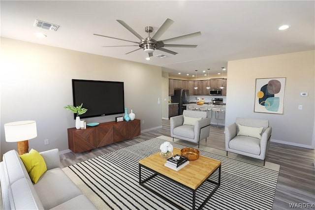 living room with baseboards, visible vents, dark wood-type flooring, and recessed lighting