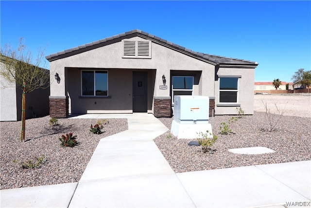 view of front of house with stone siding, a tiled roof, and stucco siding