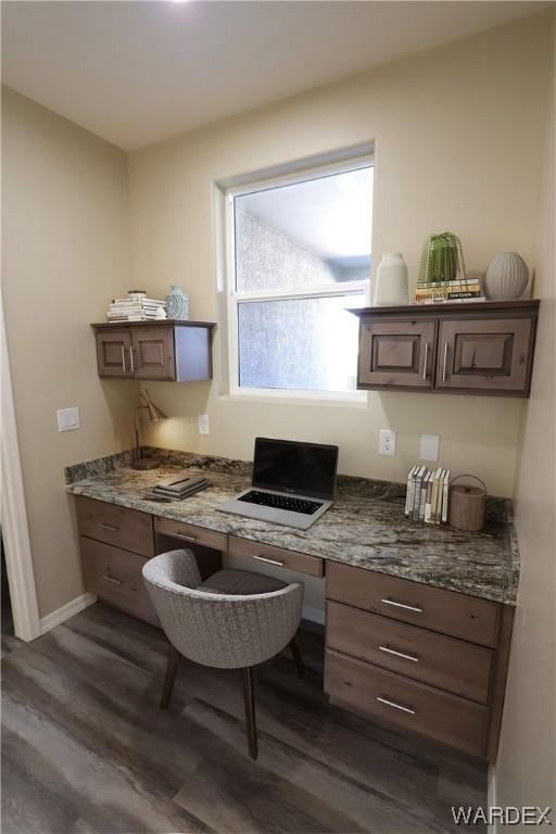 home office with dark wood-style flooring, built in study area, and baseboards