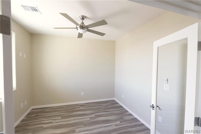 spare room with baseboards, visible vents, ceiling fan, and wood finished floors