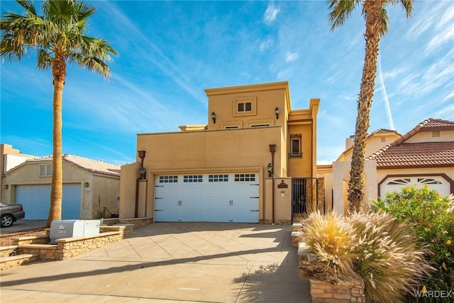 view of front of house featuring an attached garage, a gate, concrete driveway, and stucco siding