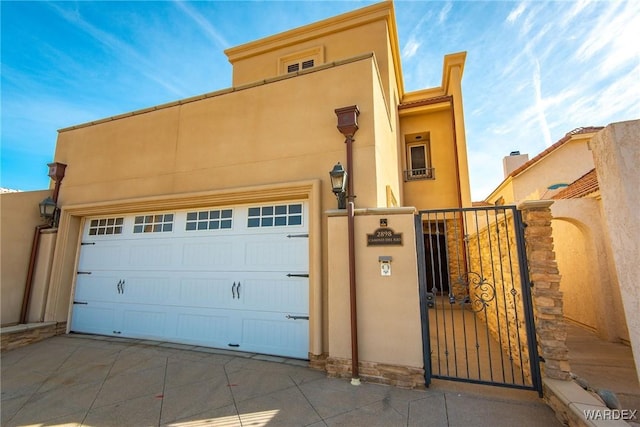 view of front of home featuring a garage, a gate, fence, and stucco siding