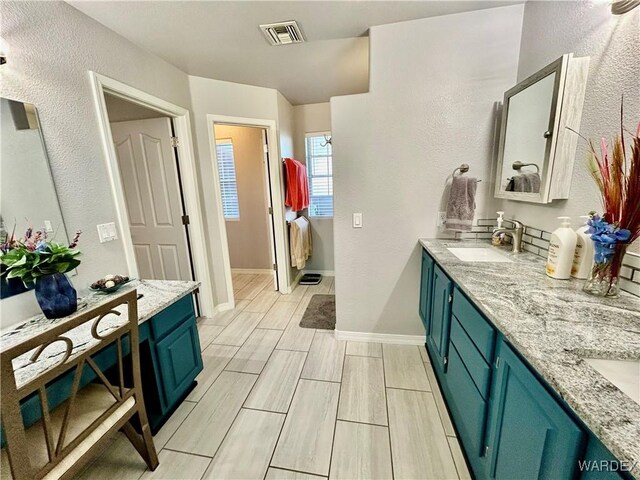 bathroom with double vanity, visible vents, wood tiled floor, a sink, and baseboards