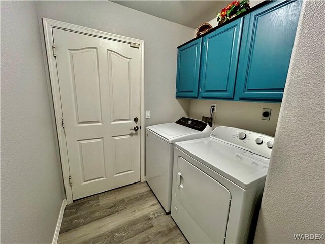 laundry area with cabinet space, separate washer and dryer, and light wood finished floors