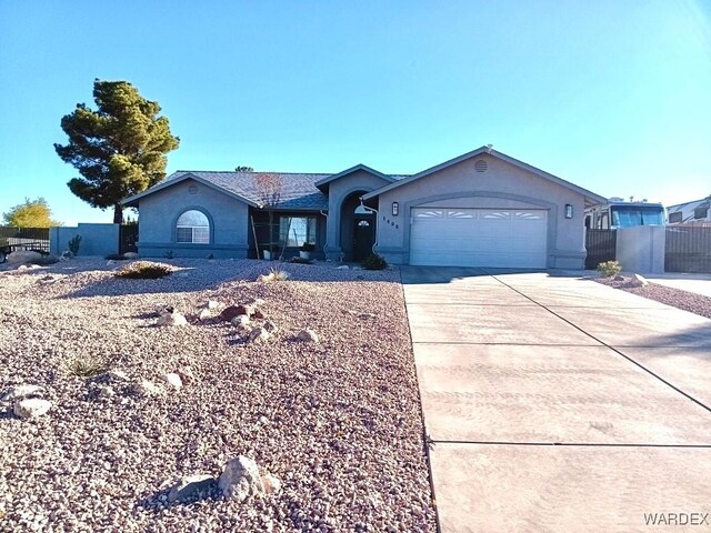 ranch-style house with a garage, driveway, fence, and stucco siding