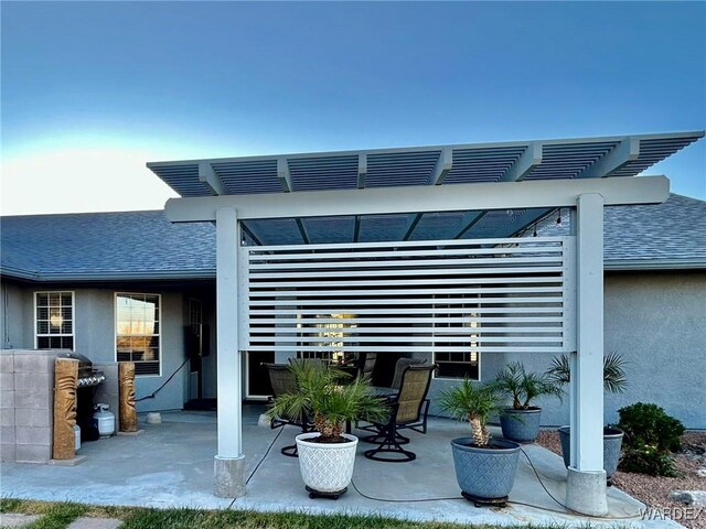 back of house featuring a patio, roof with shingles, a pergola, and stucco siding