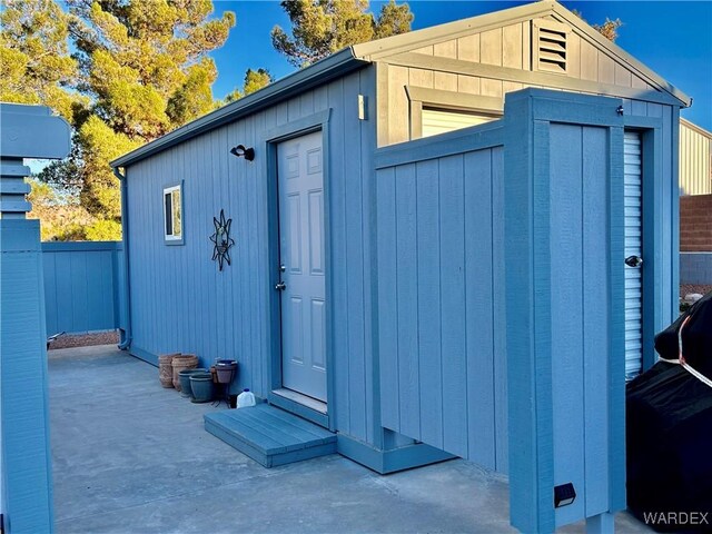 view of shed featuring entry steps and fence