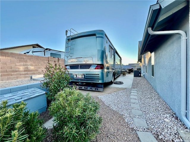 view of home's exterior featuring central AC, fence, and stucco siding