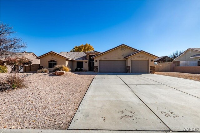 ranch-style house with a garage, driveway, stone siding, fence, and stucco siding