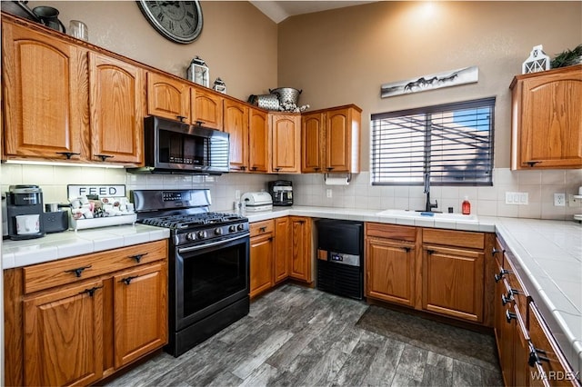 kitchen featuring range with gas cooktop, brown cabinets, a sink, and tile countertops