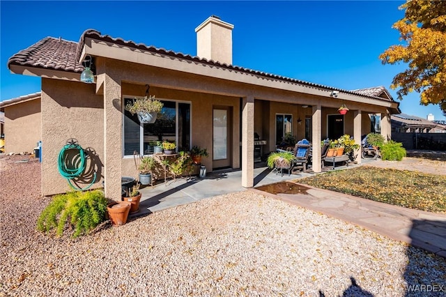 back of property with a patio area, a chimney, and stucco siding