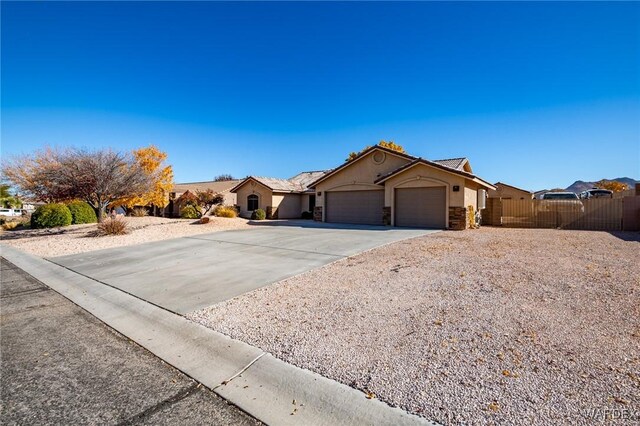 ranch-style house featuring stucco siding, concrete driveway, fence, a garage, and stone siding