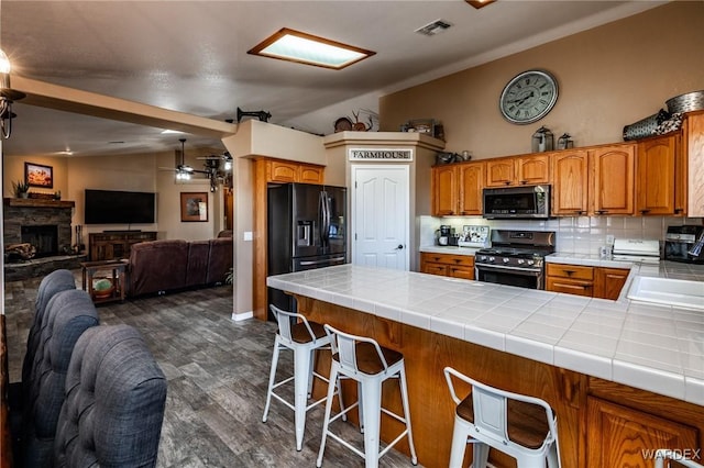 kitchen featuring tile countertops, appliances with stainless steel finishes, open floor plan, and visible vents