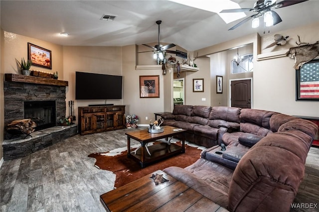 living room featuring dark wood-style floors, visible vents, ceiling fan, a stone fireplace, and high vaulted ceiling