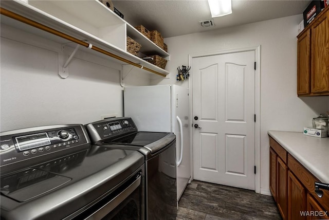 washroom featuring washer and dryer, cabinet space, dark wood finished floors, and visible vents