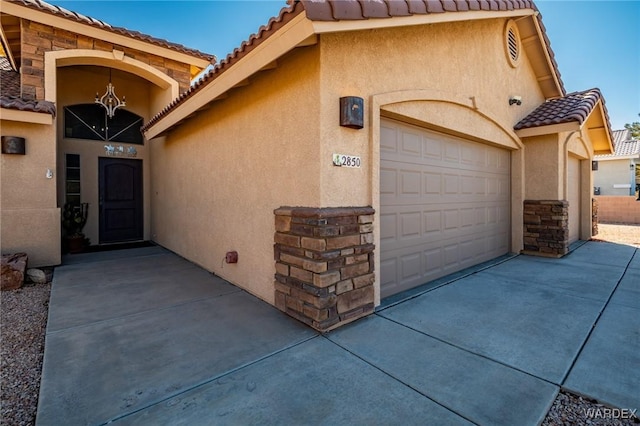 property entrance featuring a garage, stone siding, and stucco siding