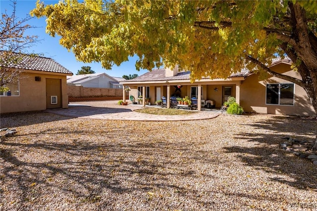 rear view of property with a patio area, fence, a tile roof, and stucco siding