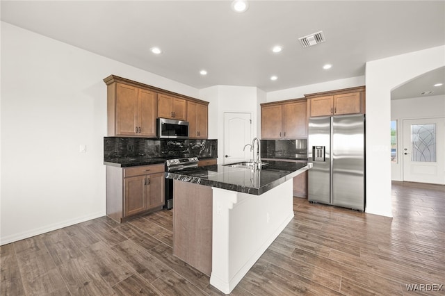 kitchen featuring dark wood-style flooring, a sink, visible vents, appliances with stainless steel finishes, and an island with sink