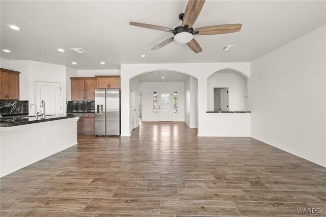 unfurnished living room featuring visible vents, arched walkways, dark wood finished floors, and recessed lighting