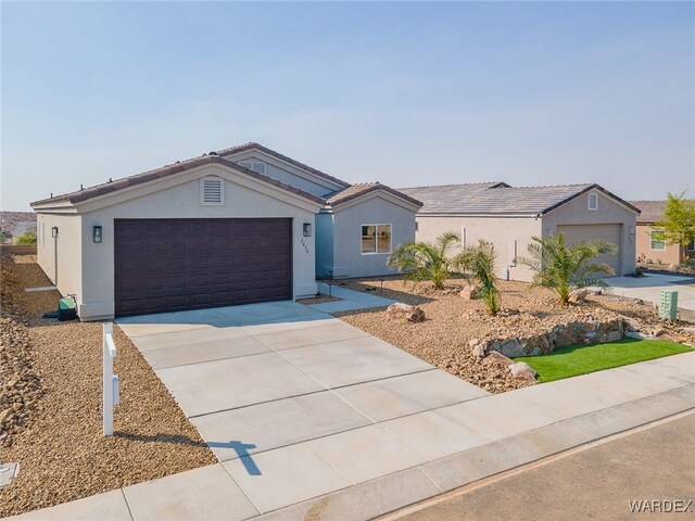 ranch-style house with concrete driveway, a tiled roof, an attached garage, and stucco siding