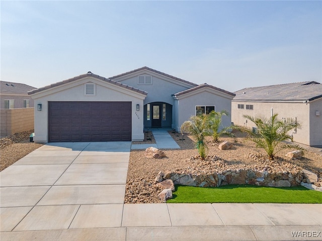 view of front facade with a garage, driveway, a tiled roof, and stucco siding