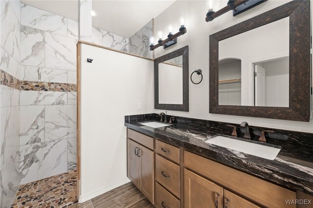 full bathroom with wood finished floors, double vanity, a sink, and a walk in shower