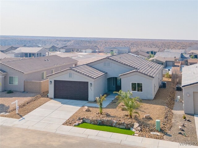 view of front of house with an attached garage, a tile roof, concrete driveway, a residential view, and stucco siding