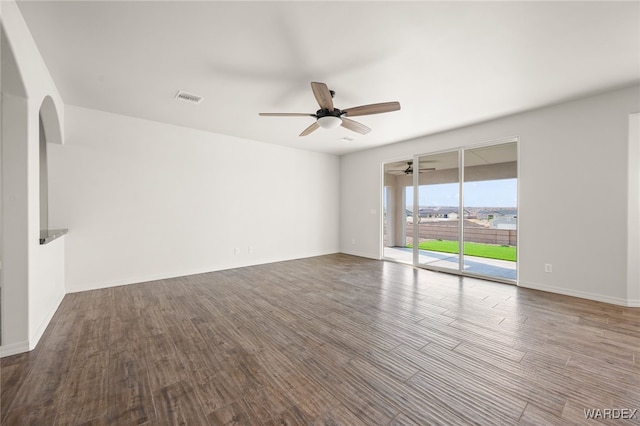 empty room with a ceiling fan, visible vents, baseboards, and wood finished floors